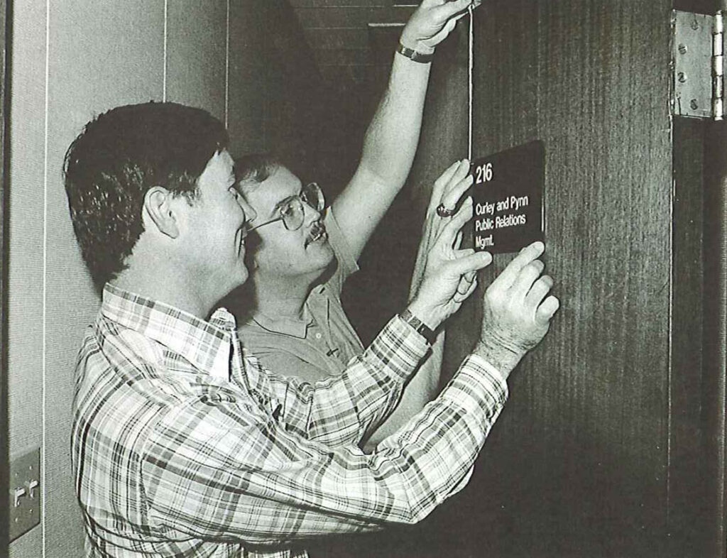 Curley & Pynn co-founders Joe Curley and Roger Pynn place a sign on their office door.